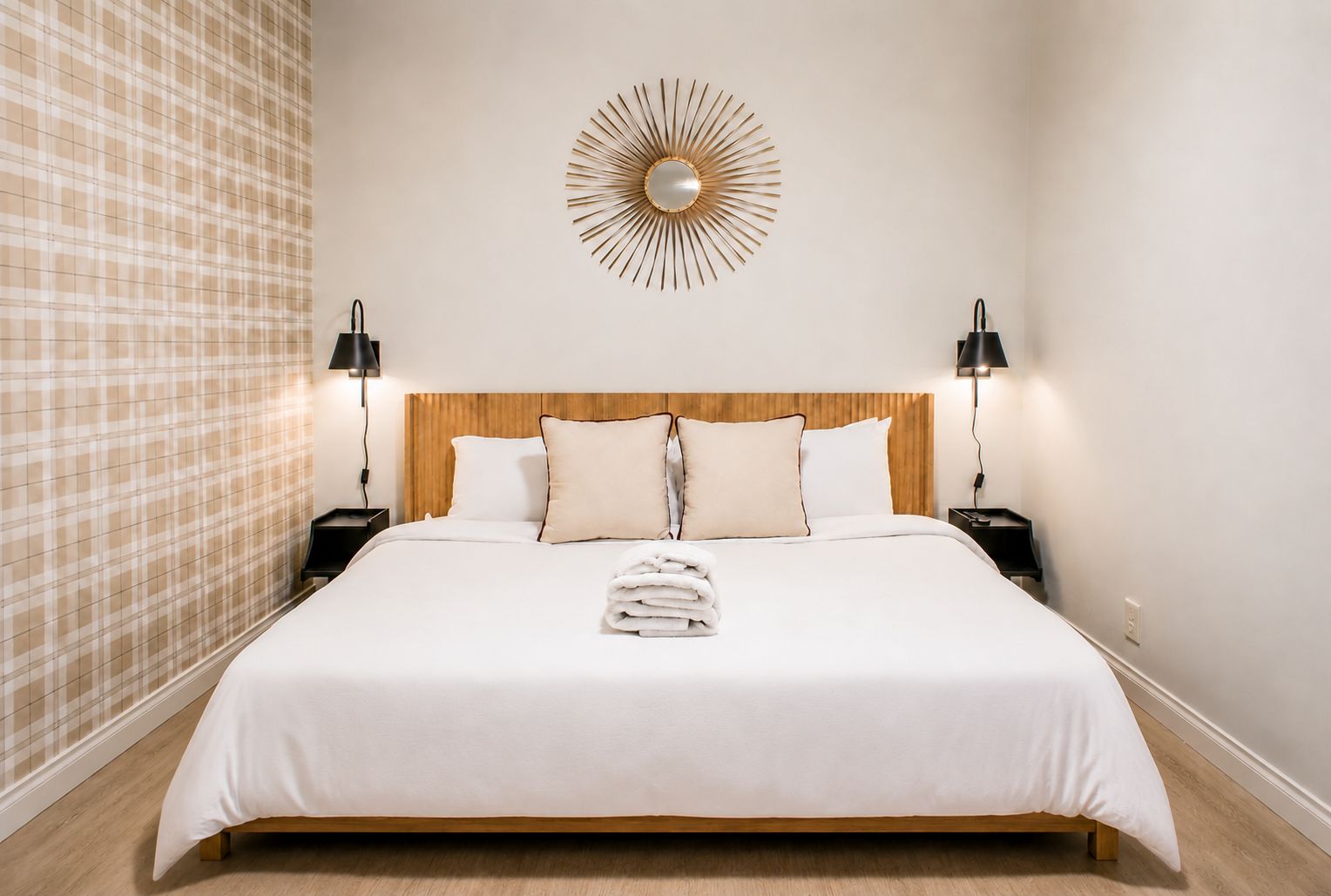 Quarto de hotel com uma cama grande, duas mesas de cabeceira, um espelho fixado na parede e cortina com padrão xadrez.