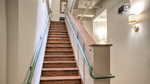 Eine Holztreppe mit Metallgeländern und einer Wandleuchte.