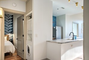 A modern kitchen with a built-in island, a washing machine, and a laundry room. - The Sapphire at Heirloom Asheville | Downtown Asheville Historic Condo (Asheville)