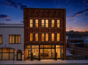 A multi-story building with a brick facade, large windows, and a ground-level entrance with a glass door. - The Sapphire at Heirloom Asheville | Downtown Asheville Historic Condo (Asheville)