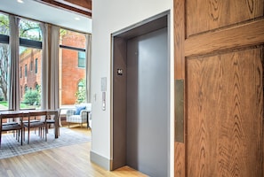An interior with a dining area, a large window, and a wooden door. - Heirloom Asheville | 8 Private Luxury Condos in Downtown Asheville (Asheville)