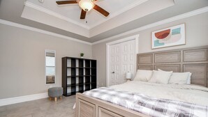 A bedroom with a wooden bed, a ceiling fan, a bookshelf, and a door. - Modern Gated Retreat w/Rooftop Views, Med Ctr & Downtown (Houston)