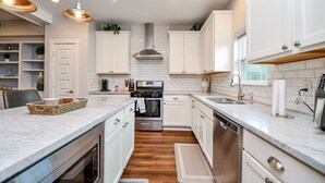 A modern kitchen with white cabinets, stainless steel appliances, and a wooden floor. - Modern Gated Retreat w/Rooftop Views, Med Ctr & Downtown (Houston)