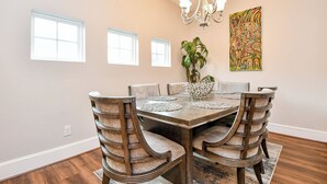 A dining room with a wooden table, six chairs, a chandelier, and a painting on the wall. - Modern Gated Retreat w/Rooftop Views, Med Ctr & Downtown (Houston)