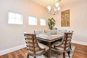 A dining room with a wooden table, six chairs, a chandelier, and a painting on the wall. - Modern Gated Retreat w/Rooftop Views, Med Ctr & Downtown (Houston)