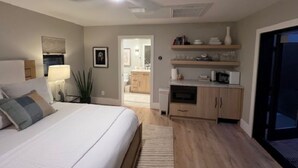Ein Schlafzimmer mit Bett, Nachttisch, Lampe und Blick ins Bad.
