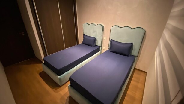 Twee eenpersoonsbedden met hoofdborden, een houten vloer en een deur op de achtergrond.