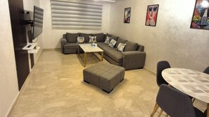 Een moderne woonkamer met een modulaire bank, een salontafel en een eettafel met stoelen.