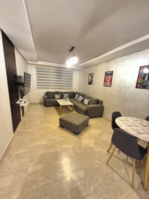 A modern living room with a sectional sofa, a coffee table, and a dining table with chairs. - Spacious and bright - 2 bedrooms ready to welcome you! (Marrakech)