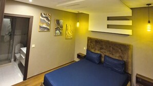 Een moderne slaapkamer met een groot bed, een douchegedeelte en kunstwerken aan de wanden.
