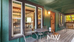 A porch with a table and chairs, a lamp, and a door. - Downtown CDA Retreat – Hot Tub, Deck, & Walk to Lake! (Coeur D Alene)