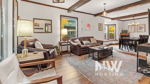 A spacious living room with a leather sofa, a coffee table, and a dining area with a wooden table and chairs. - Downtown CDA Retreat – Hot Tub, Deck, & Walk to Lake! (Coeur D Alene)
