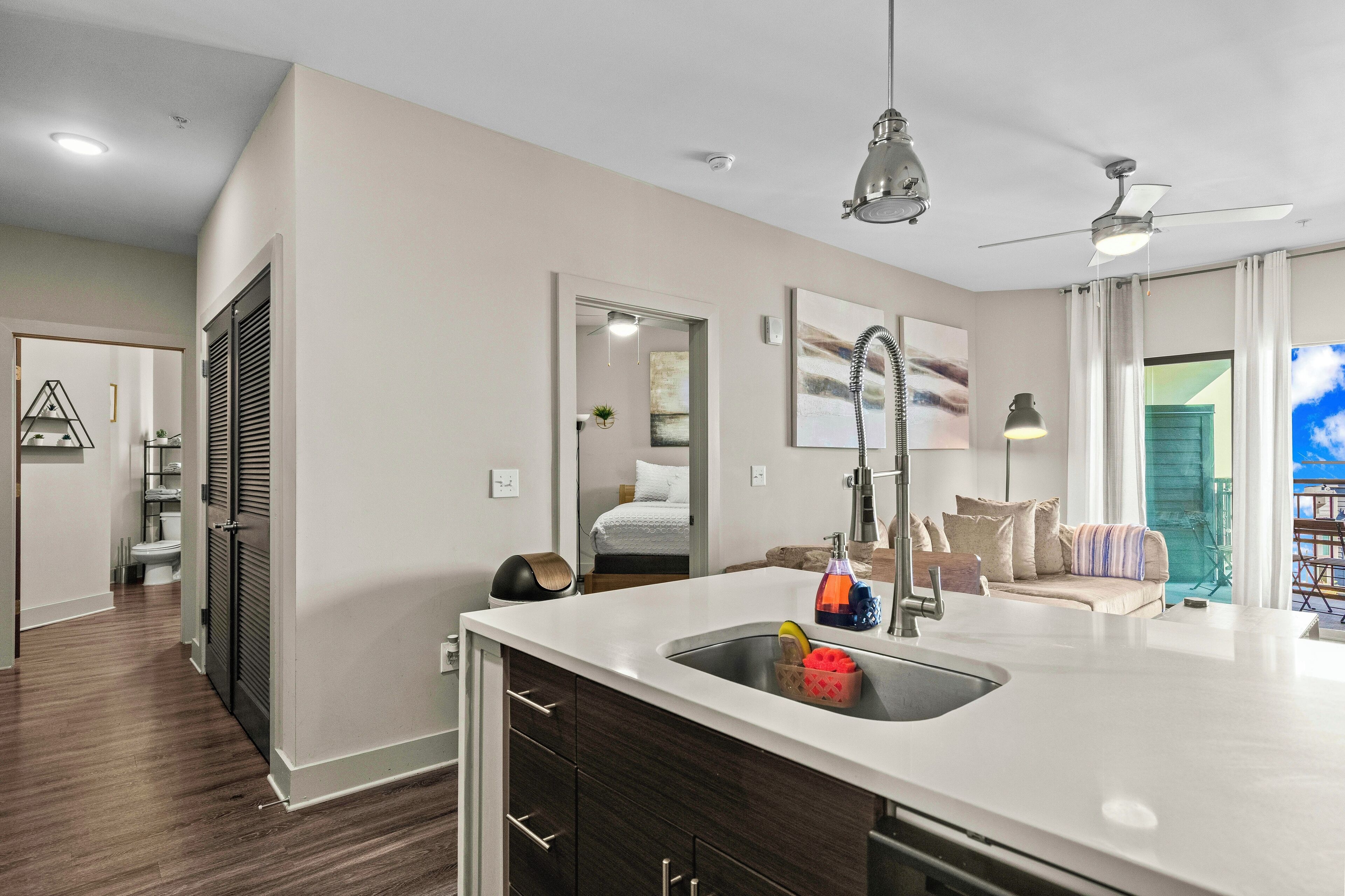 A modern kitchen with a large island, a built-in sink, and a ceiling fan.