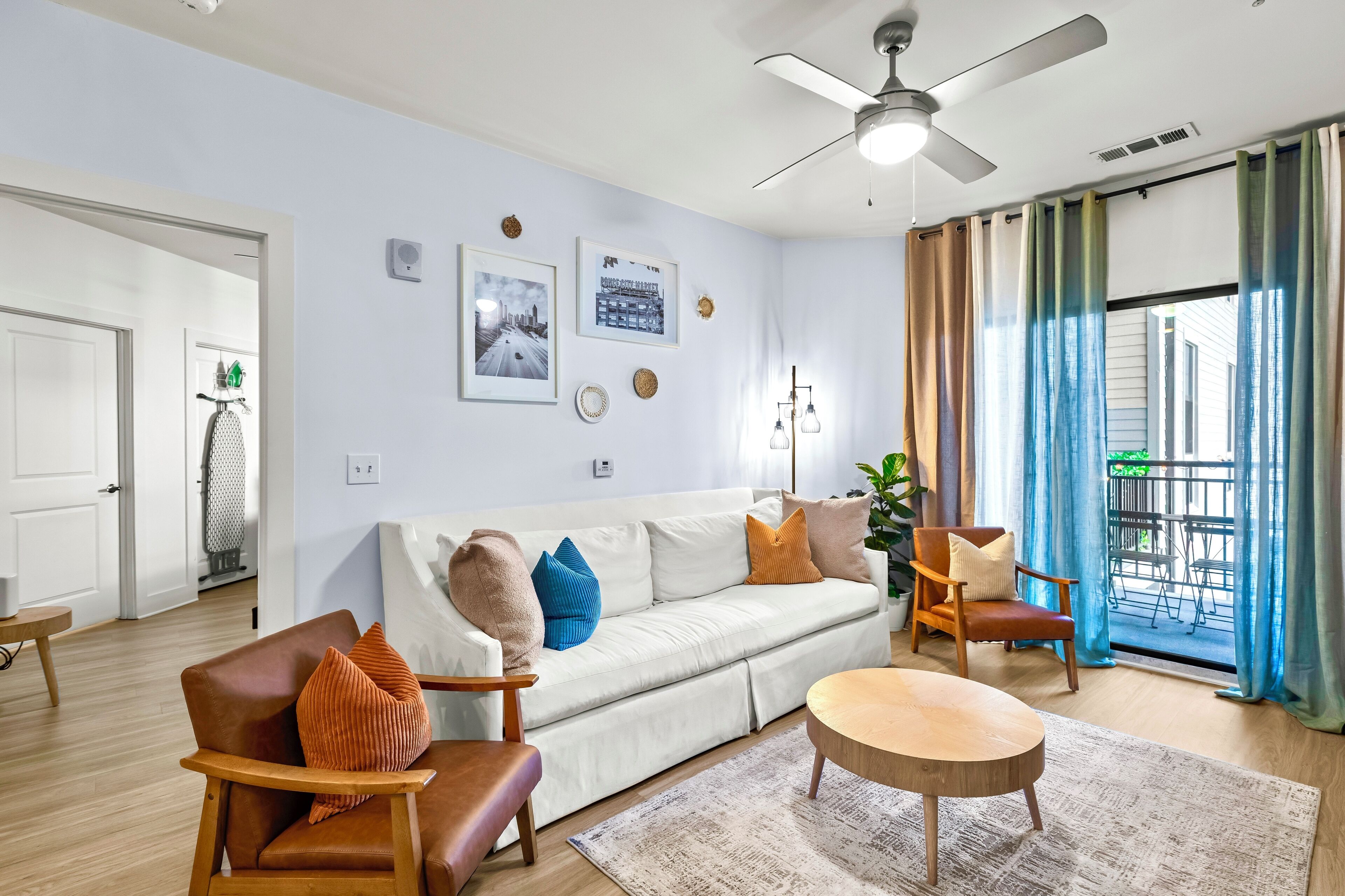 A living room with a white sofa, brown leather chairs, a wooden coffee table, and a ceiling fan.