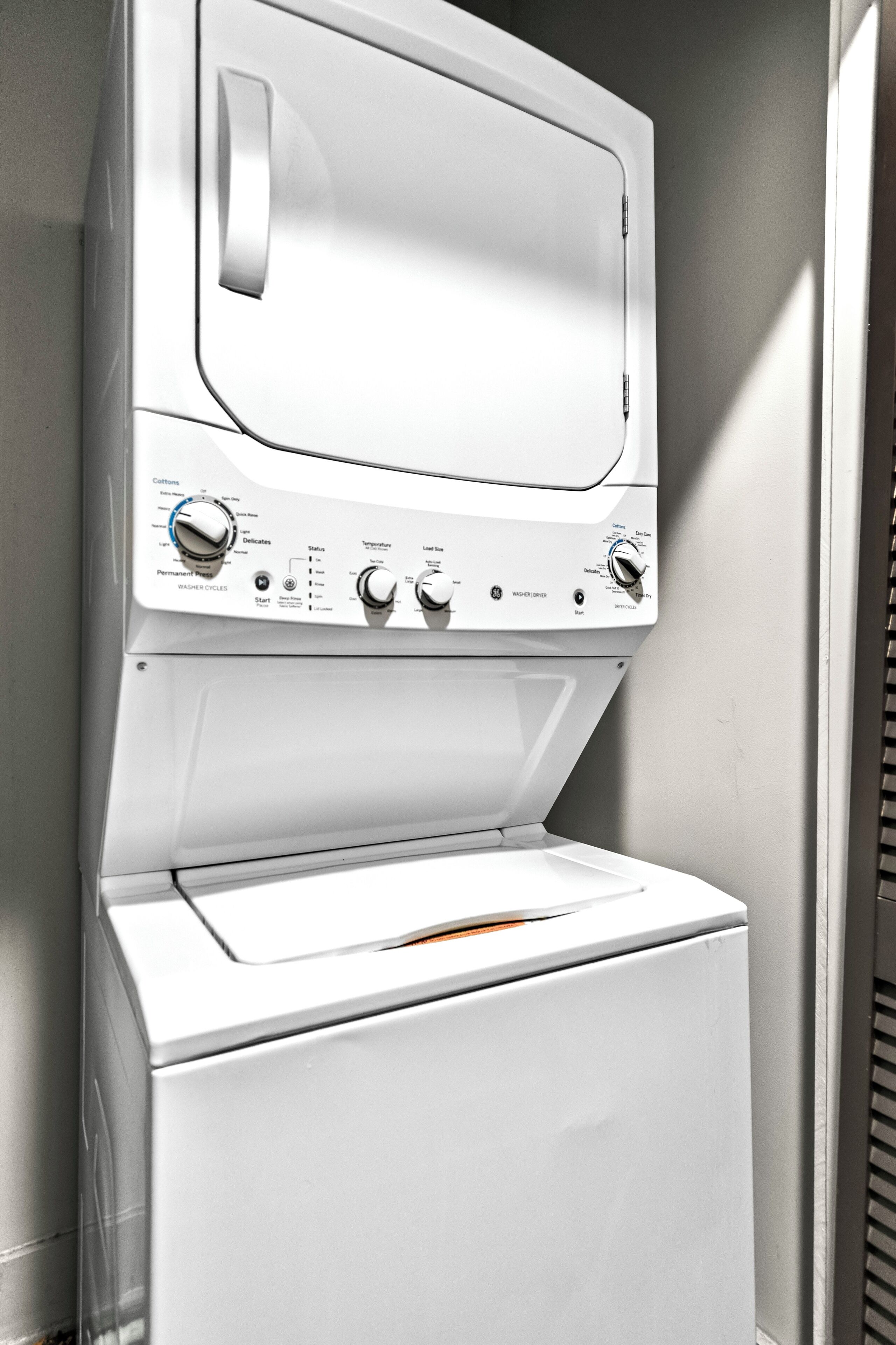 A white washer and dryer unit with control knobs and a front-loading door.