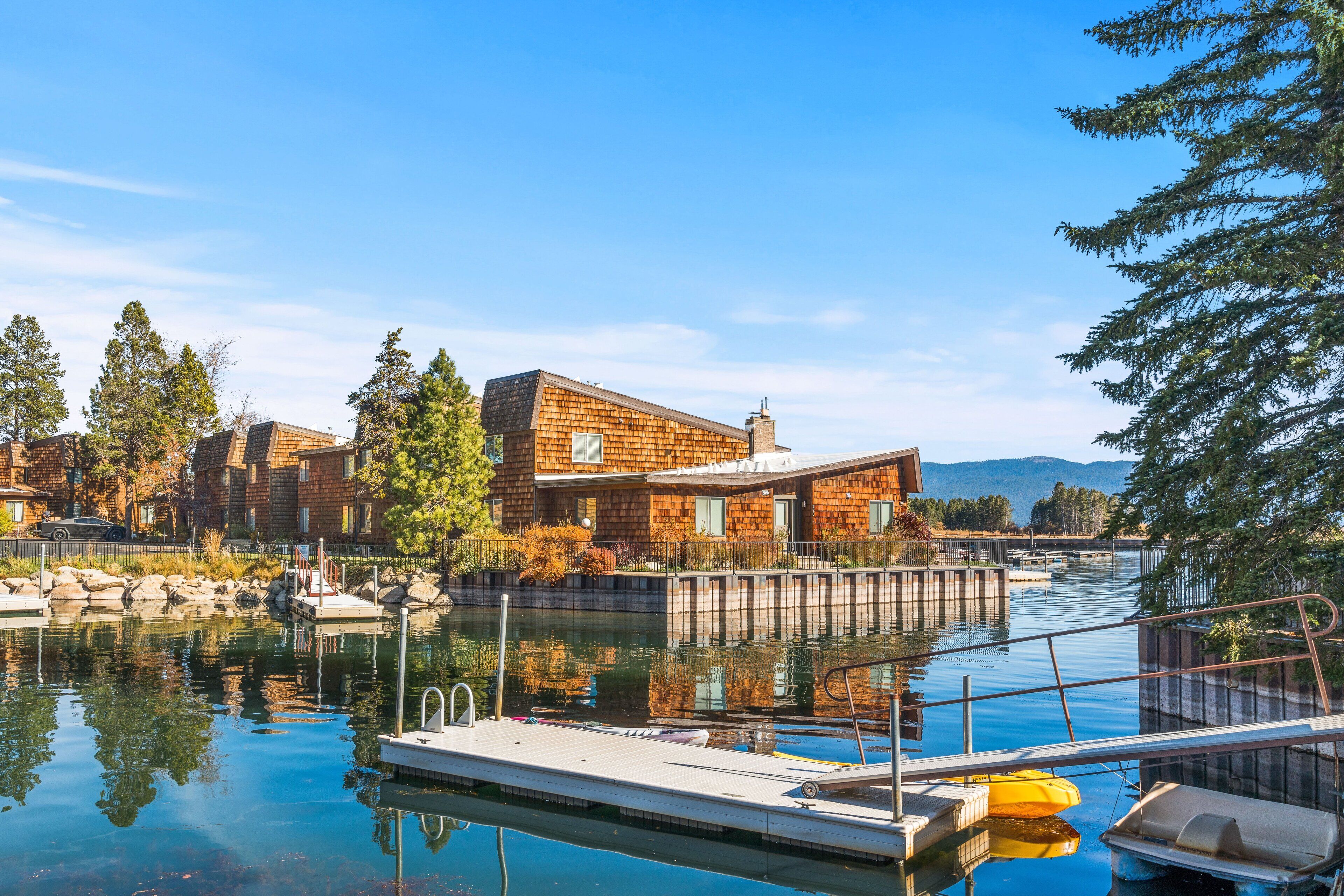 A waterfront property with a dock, wooden buildings, and a clear view of the water.