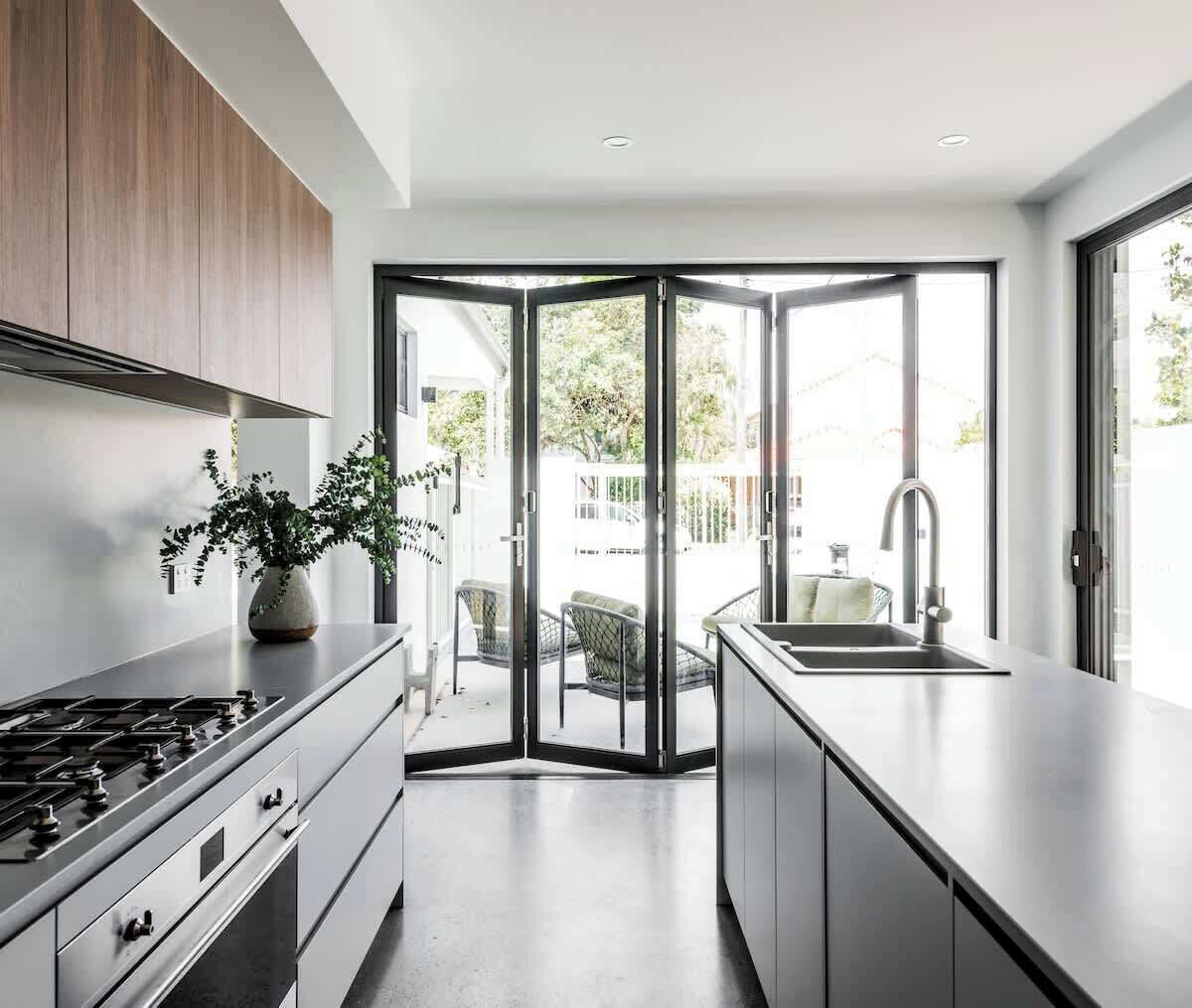 A modern kitchen with a gas stove, a sink, and a plant on the counter.