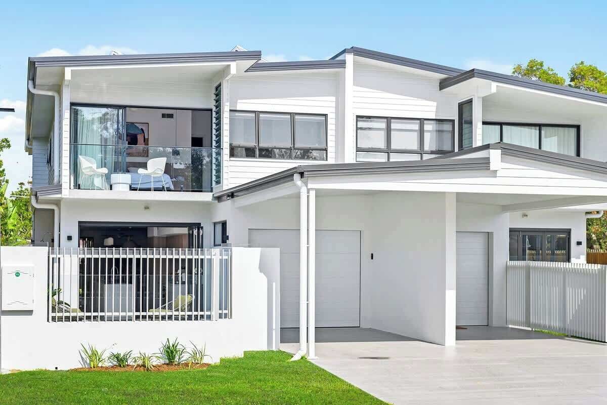 A modern two-story house with a covered driveway, a garage, and a balcony with outdoor seating.