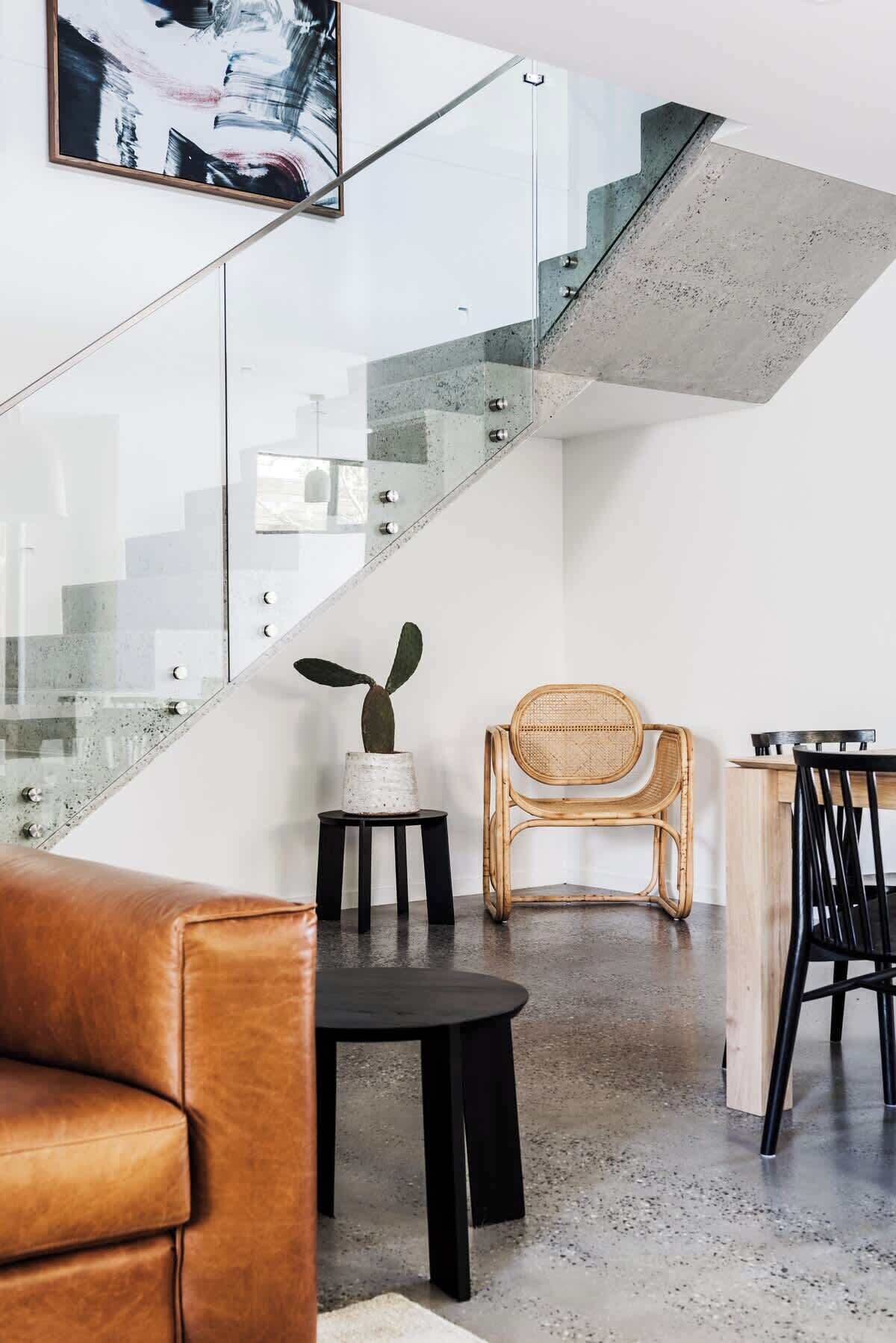 A modern interior with a staircase, a leather sofa, a dining table, and a chair.