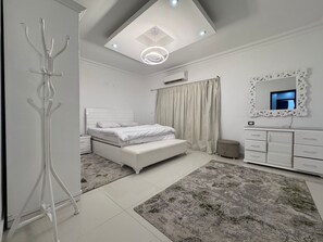 Ein modernes Schlafzimmer mit Bett, Nachttischen, Schminktisch mit Spiegel und Deckenleuchte.