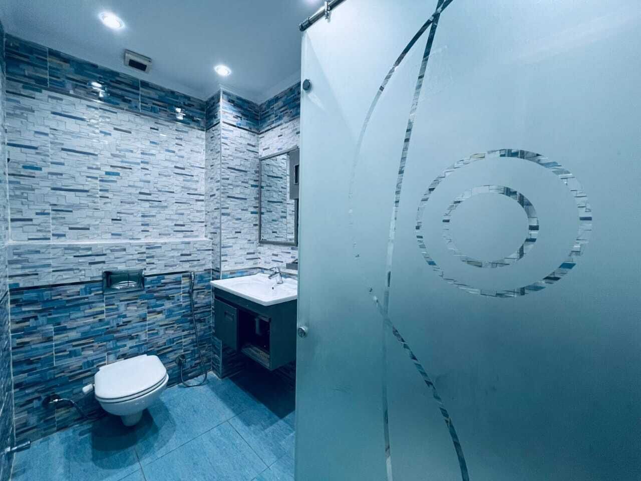 Une salle de bain avec un mur carrelé, des toilettes et un lavabo.