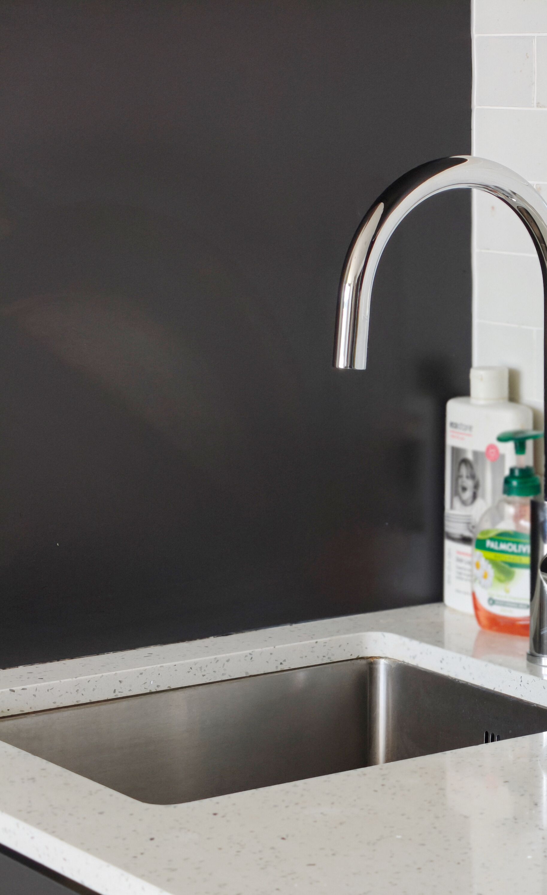 A kitchen with a stainless steel sink, a modern faucet, and white storage containers on the counter.