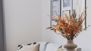 En spiseplads med et rundt bord, sorte stole og en vase med udtørrede blomster.