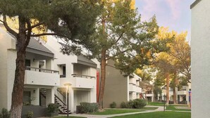 Un edificio residencial con varios balcones, un césped cuidado y árboles.