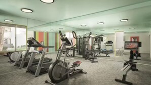 Un gimnasio moderno con máquinas de cardio, equipo de levantamiento de pesas y una televisión para entretenimiento.