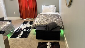 Een slaapkamer met een bed, nachtkastje, spiegel en een rood gordijn.