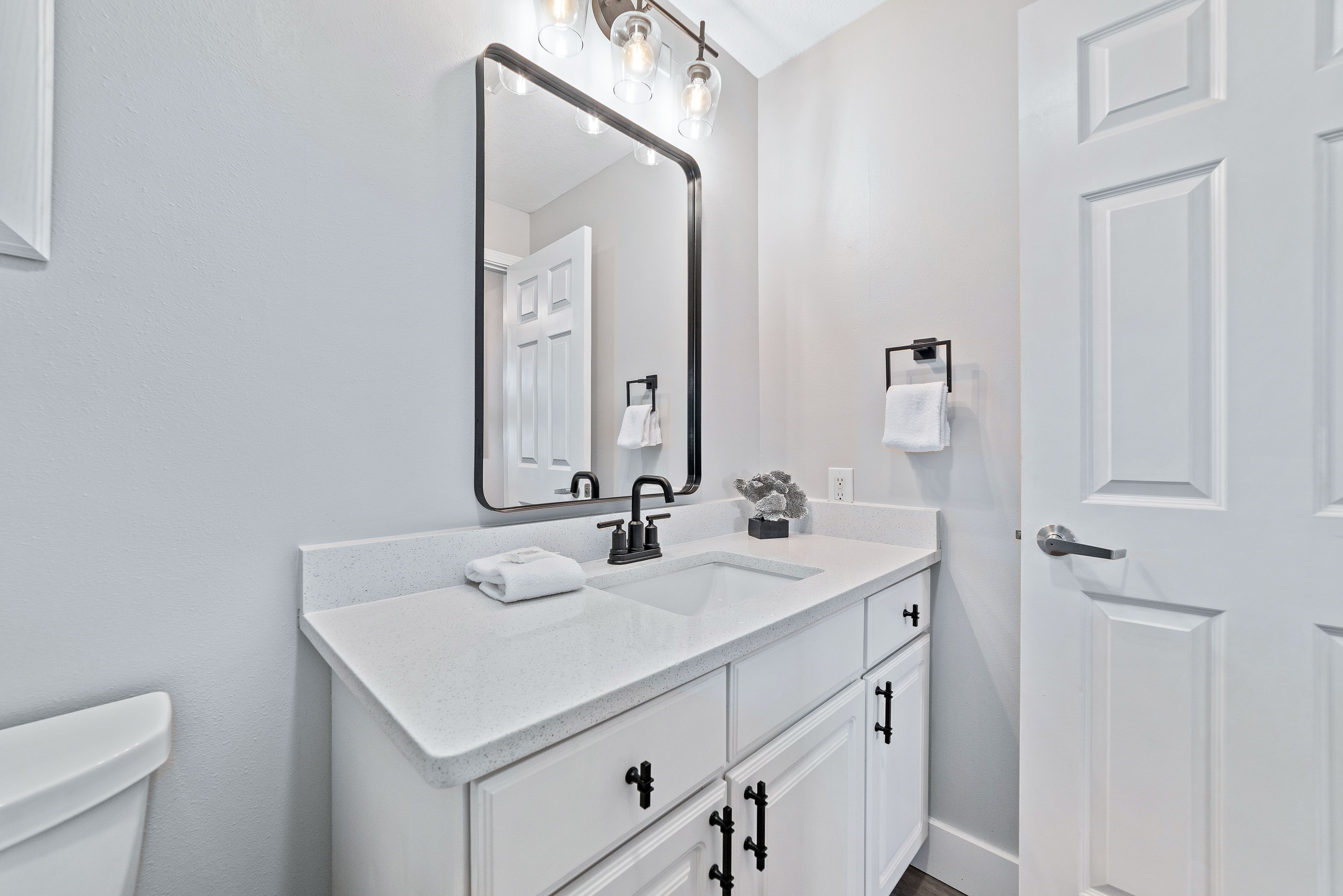 A modern bathroom with a white vanity, a large mirror, and a sink.