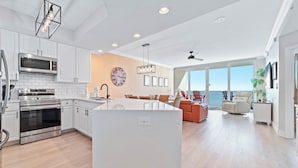 A modern kitchen with white cabinets, stainless steel appliances, and a large island. - Modern Beachfront Luxury | Balcony Grill, Gulf Views & Pool Access | BEACHBALL PROPERTIES (Gulf Shores)