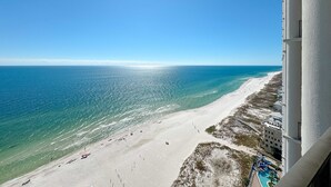 Ein Hochhaus-Hotel mit Blick auf einen Strand, kristallklares blaues Wasser und einen Sandstrand.