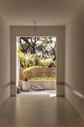 A corridor with a view of a garden area, including a potted plant and a small rock garden. - Wan'an Waves Wild Luxury Designer Hotel (Xishuangbanna Dai)