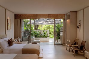 A spacious bedroom with a large bed, a seating area with chairs, and a view of a lush garden through a sliding glass door. - Wan'an Waves Wild Luxury Designer Hotel (Xishuangbanna Dai)
