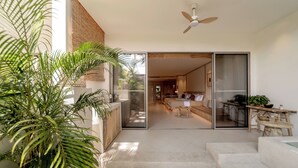 Un intérieur moderne avec un escalier menant à un espace de vie, un ventilateur de plafond et une grande plante.