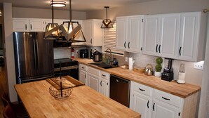 Una cucina moderna con mobili bianchi, elettrodomestici in acciaio inossidabile e piani in legno.