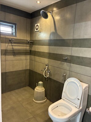 A modern bathroom with a shower, toilet, and a towel rack. - Family Castle Munnar (Devikolam)