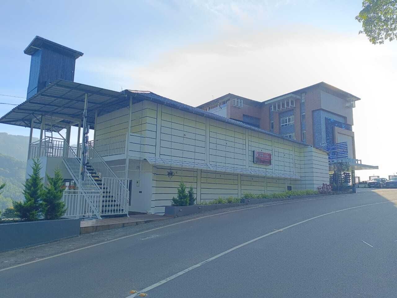 A multi-story building with a covered staircase, a flat roof, and a sign indicating a business or commercial use.