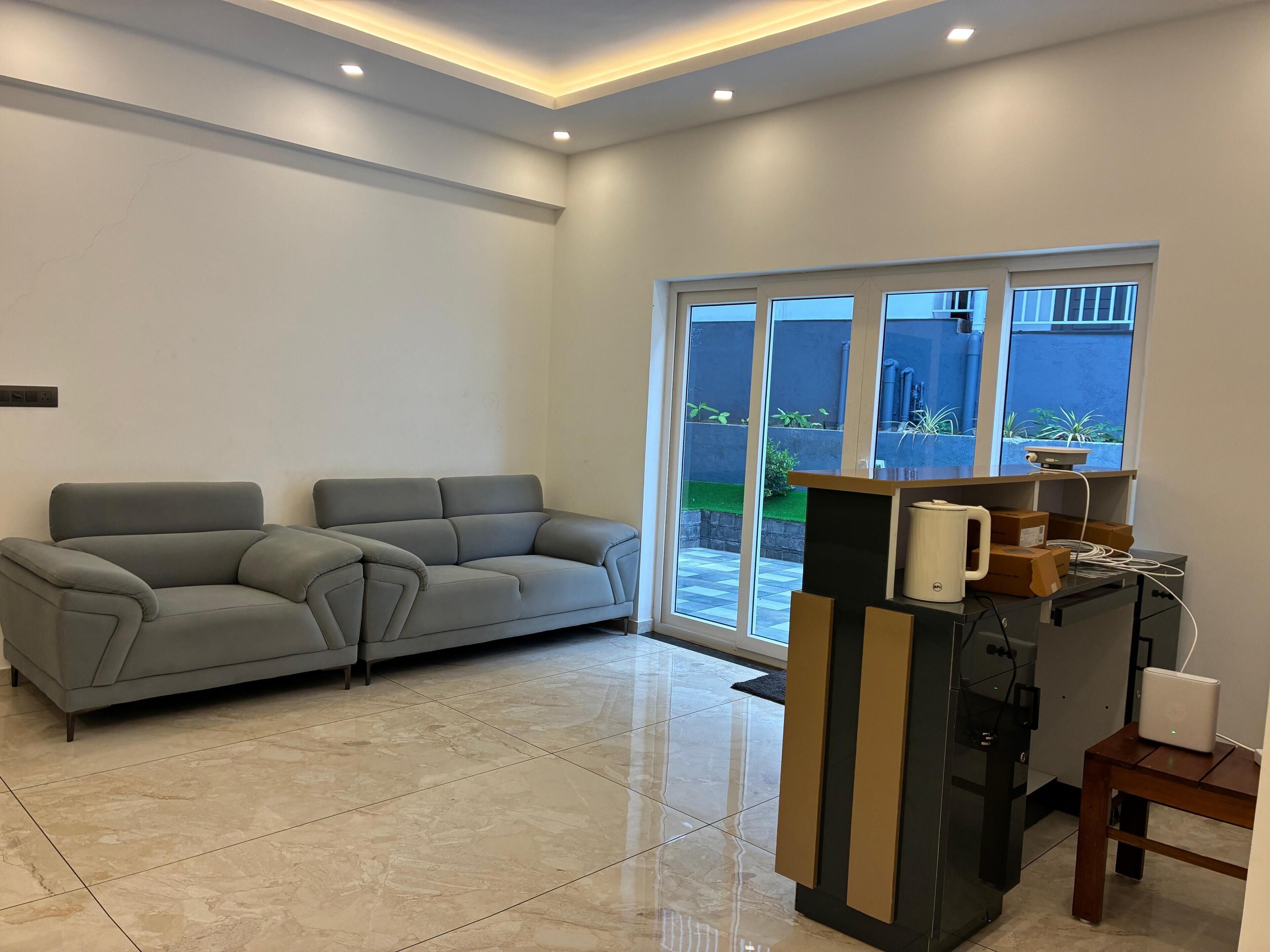 Una sala de estar moderna con un sofá gris, una cafetera y una mesita.