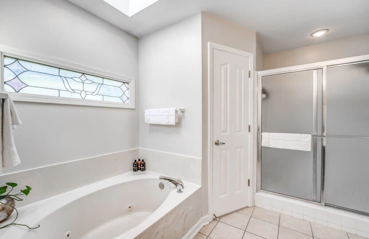 Un baño con una bañera independiente, cabina de ducha de cristal y una ventana de vitral.