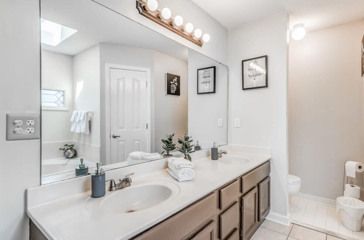 Un baño moderno con dos lavamanos, un espejo grande y un mueble tocador con cajones.