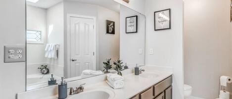 Un baño moderno con dos lavamanos, un espejo grande y un mueble tocador con cajones.