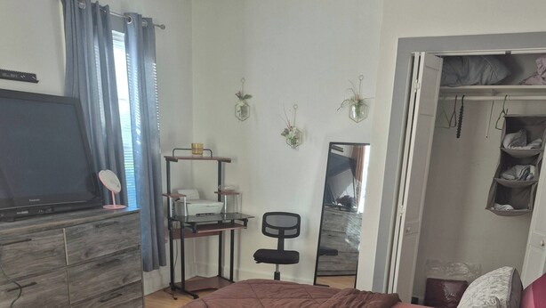 Un dormitorio con cama, escritorio, silla, armario y televisor.