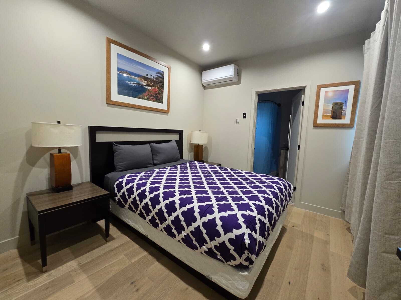 A neatly arranged bedroom with a bed, bedside tables, and two framed pictures on the walls.