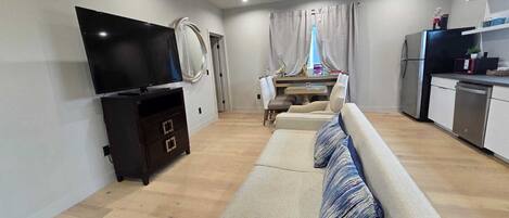 A modern living room with a sofa, TV, and dining area.
