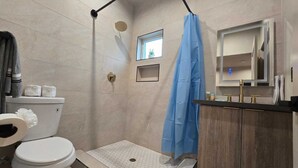 Une salle de bain avec douche, toilettes et lavabo.