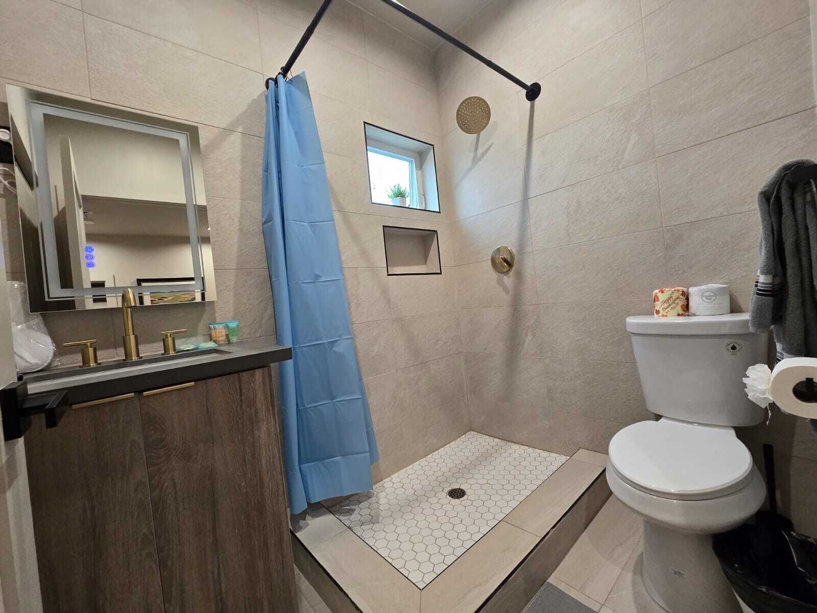 A modern bathroom with a shower, toilet, and sink.