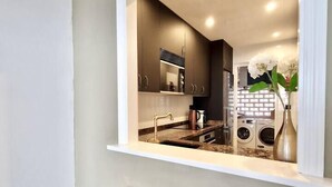 Une cuisine moderne dotée d’un îlot central intégré, d’appareils électroménagers en acier inoxydable et de tabourets en bois.
