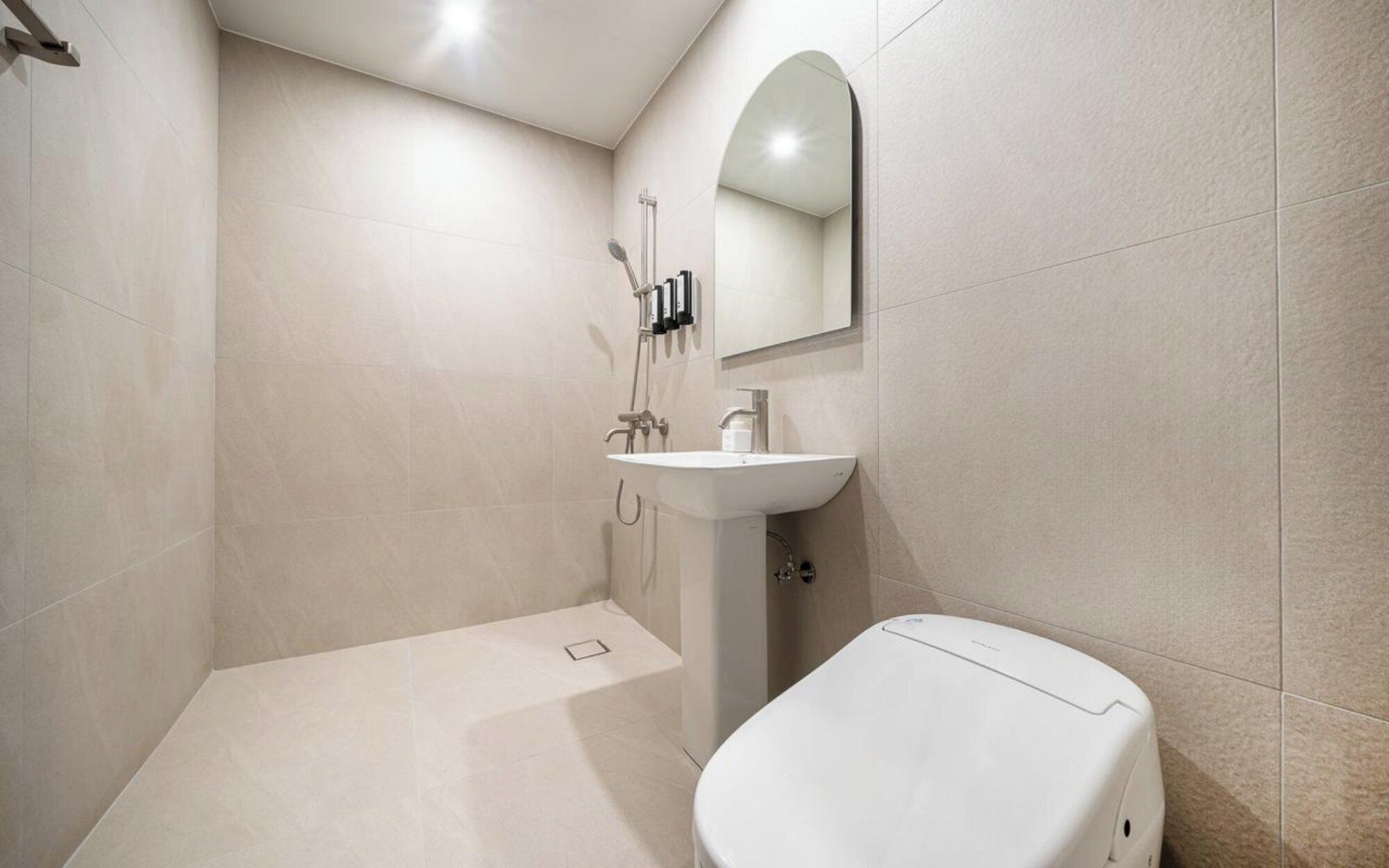 Un baño moderno con un lavamanos blanco, un espejo encima y un inodoro.